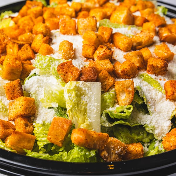Close-up of a Caesar salad with crisp romaine lettuce, abundant croutons, and grated Parmesan cheese.