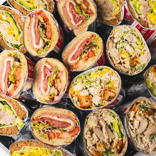 An overhead view of various sandwiches and wraps, some cut in half, showcasing their fillings.