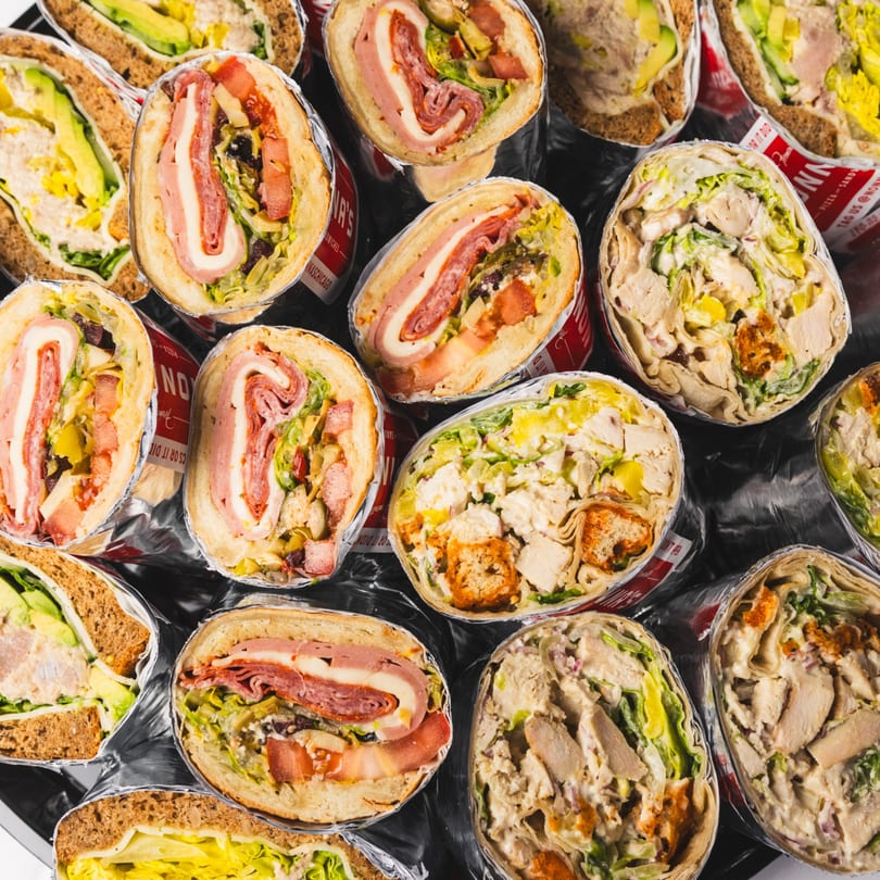 An overhead view of various sandwiches and wraps, some cut in half, showcasing their fillings.